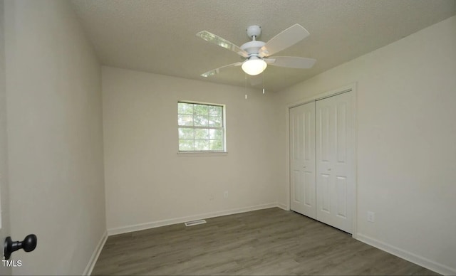 unfurnished bedroom featuring hardwood / wood-style flooring, a textured ceiling, ceiling fan, and a closet