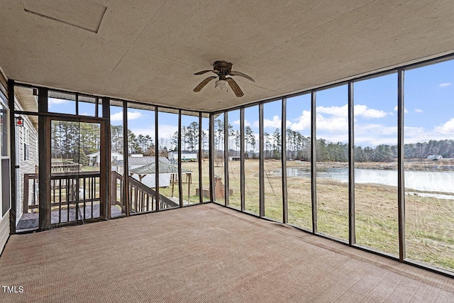 unfurnished sunroom featuring ceiling fan and a water view