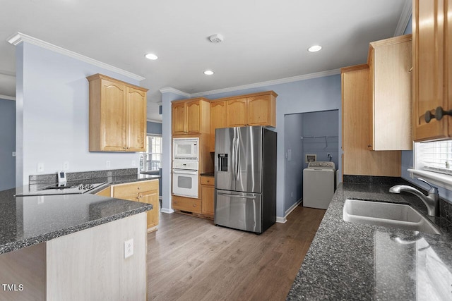 kitchen featuring white appliances, washer / dryer, wood-type flooring, sink, and kitchen peninsula