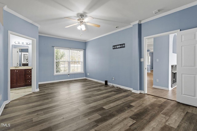 unfurnished bedroom featuring ensuite bathroom, ceiling fan, dark wood-type flooring, and ornamental molding