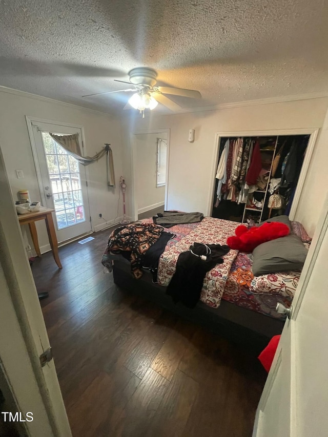 bedroom featuring ceiling fan, a closet, dark hardwood / wood-style flooring, a textured ceiling, and crown molding