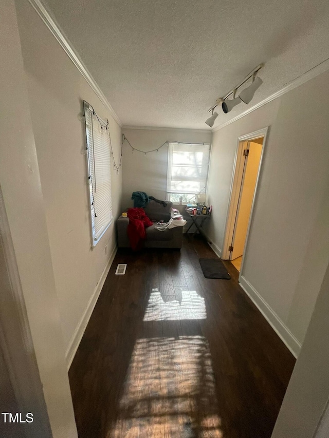 interior space with a textured ceiling, ornamental molding, rail lighting, and dark hardwood / wood-style floors