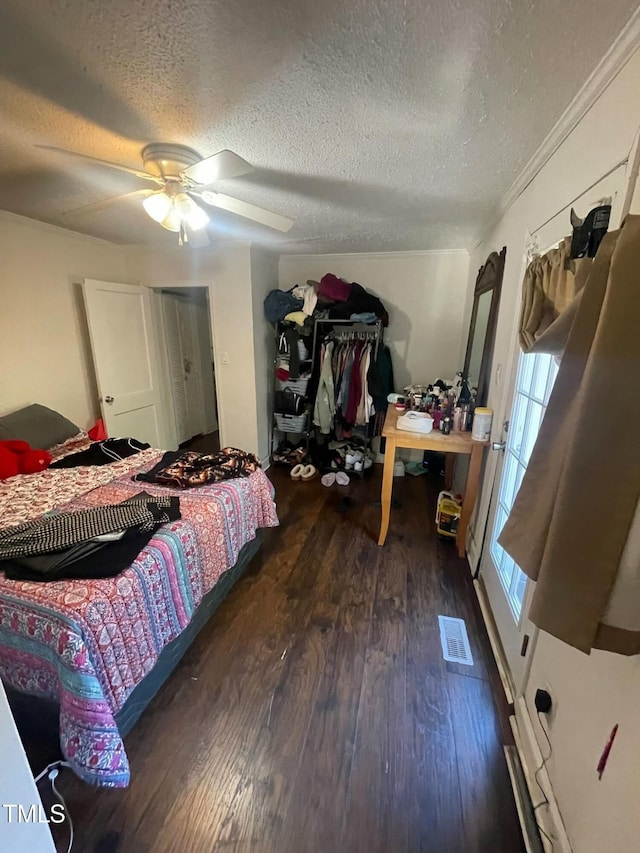 bedroom featuring ceiling fan, a textured ceiling, dark hardwood / wood-style floors, and ornamental molding