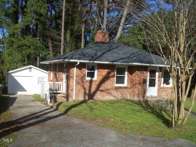 ranch-style home with a garage, a front lawn, and an outbuilding