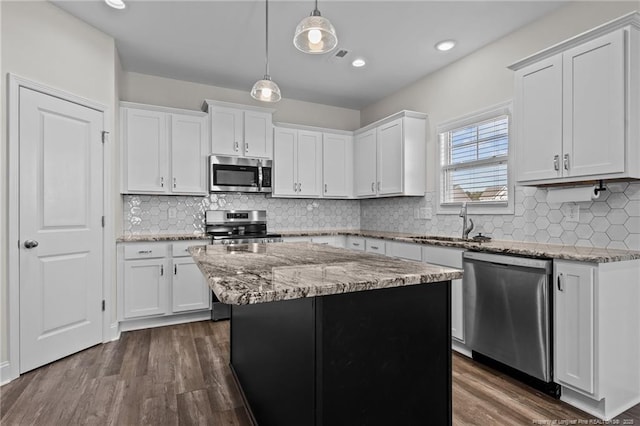 kitchen featuring light stone counters, appliances with stainless steel finishes, white cabinets, and a kitchen island