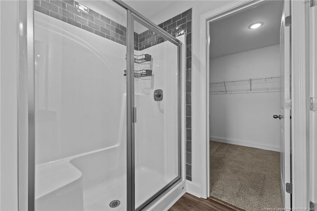 bathroom with a shower with shower door and wood-type flooring