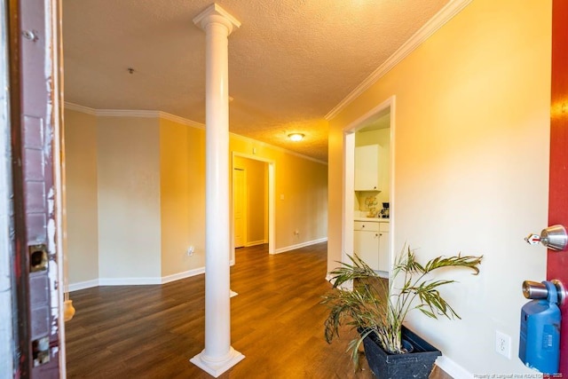 foyer entrance featuring a textured ceiling, ornate columns, ornamental molding, and dark hardwood / wood-style floors