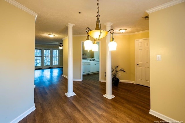 unfurnished dining area featuring dark wood-type flooring, ornamental molding, ornate columns, and ceiling fan