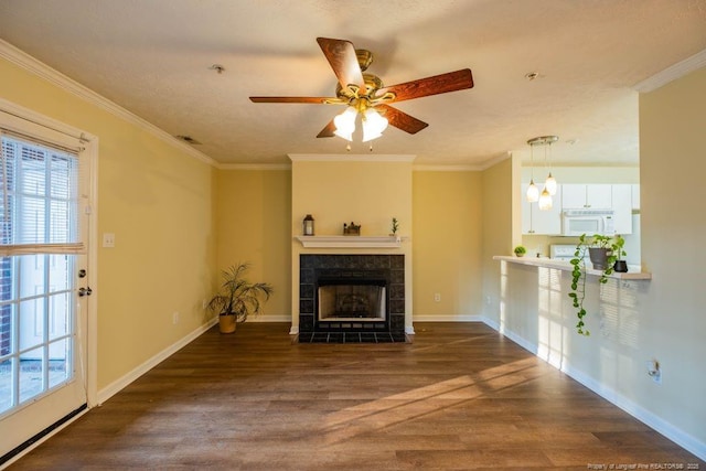 living room with ceiling fan, dark hardwood / wood-style floors, a tile fireplace, and crown molding