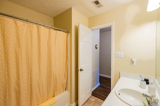 bathroom featuring a textured ceiling, vanity, and shower / tub combo with curtain