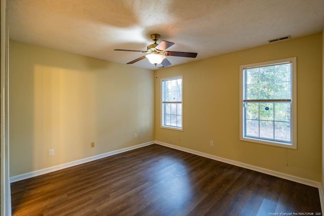 unfurnished room featuring ceiling fan, a healthy amount of sunlight, dark wood-type flooring, and a textured ceiling