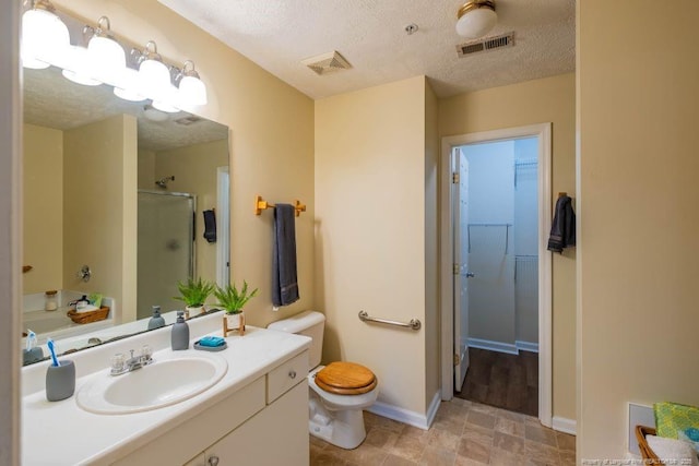 bathroom featuring a textured ceiling, toilet, walk in shower, and vanity