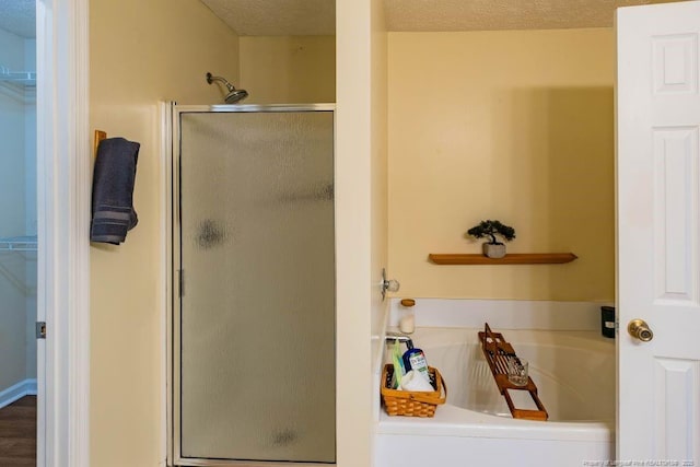 bathroom featuring a textured ceiling and shower with separate bathtub