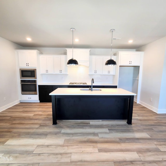 kitchen featuring a center island with sink, stainless steel appliances, white cabinetry, and sink