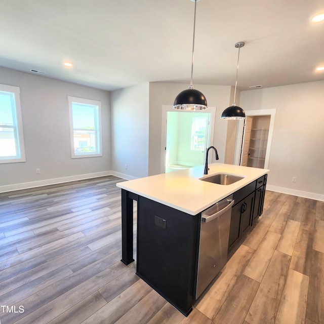 kitchen with a center island with sink, plenty of natural light, dishwasher, hanging light fixtures, and sink