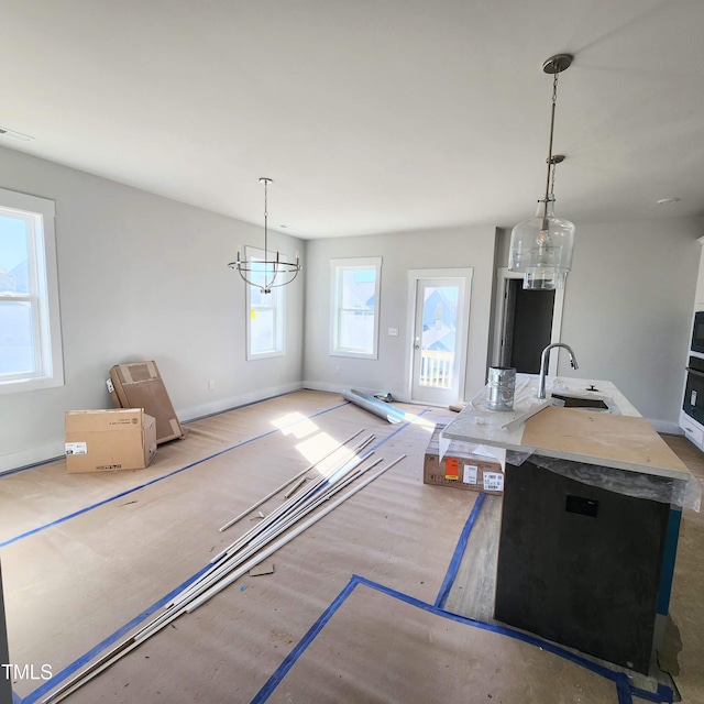 kitchen with sink, hanging light fixtures, oven, and a notable chandelier