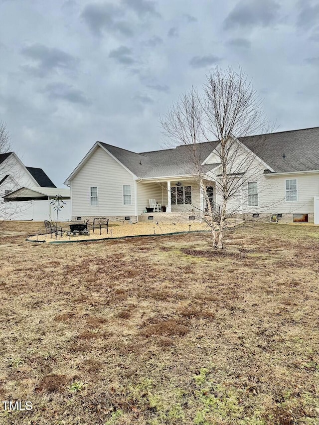 rear view of house with an outdoor fire pit and a yard