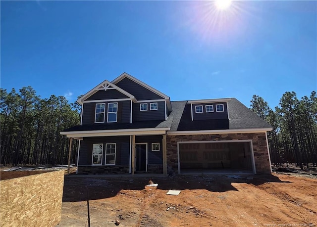 view of front of property featuring a porch, stone siding, and an attached garage