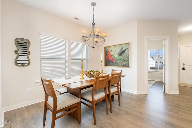 dining area featuring wood-type flooring and a notable chandelier