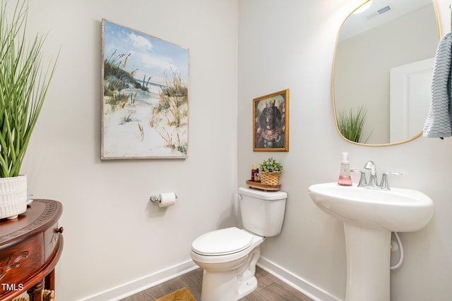 bathroom featuring toilet, sink, and hardwood / wood-style floors