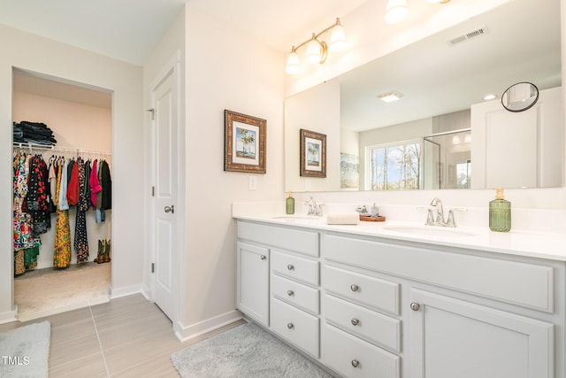 bathroom with a shower with door, tile patterned floors, and vanity