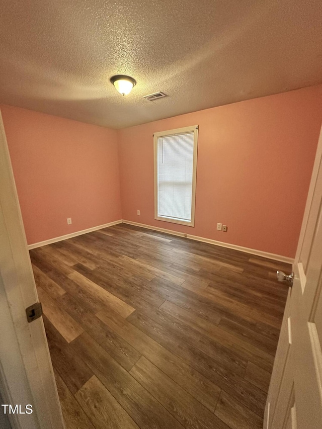 empty room featuring a textured ceiling and dark hardwood / wood-style floors