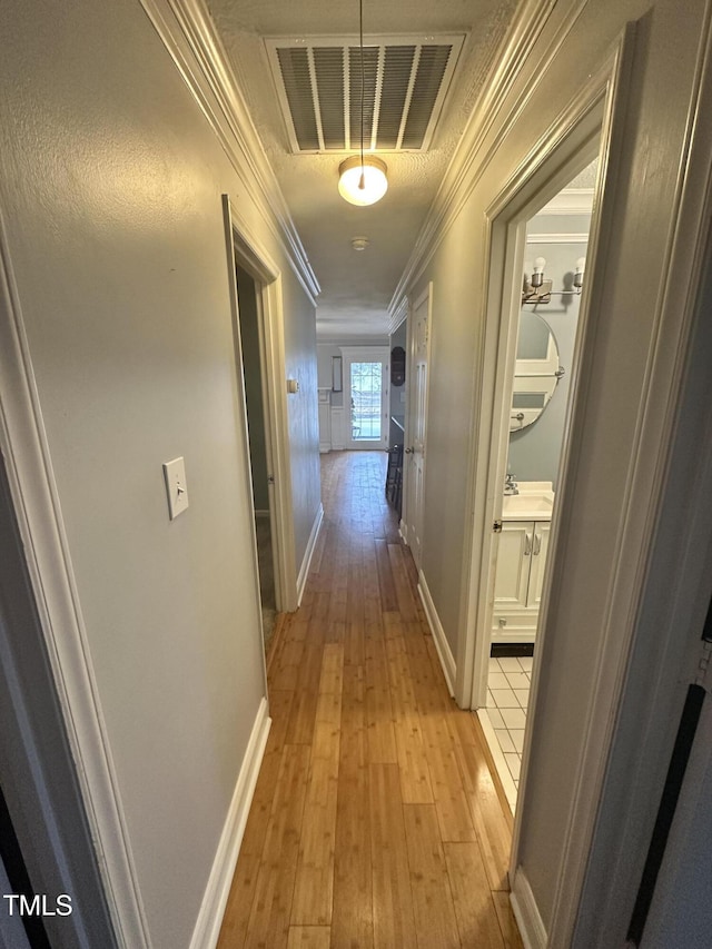 hall with light hardwood / wood-style floors and ornamental molding