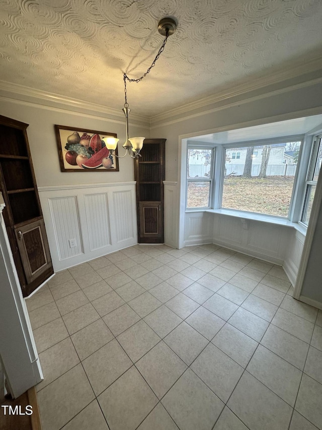 unfurnished dining area featuring a textured ceiling, ornamental molding, and a chandelier