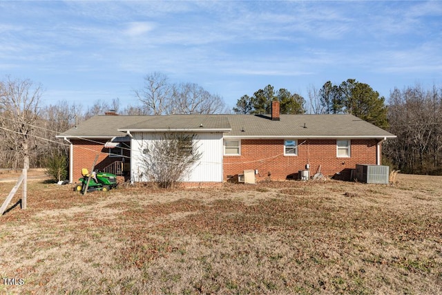 back of house with central AC unit and a yard