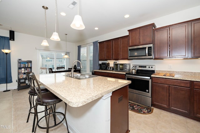 kitchen featuring appliances with stainless steel finishes, sink, an island with sink, and hanging light fixtures