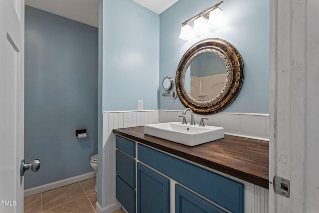 bathroom featuring toilet, vanity, tile patterned floors, and a textured ceiling