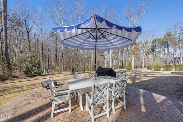 view of patio with outdoor dining space and a view of trees