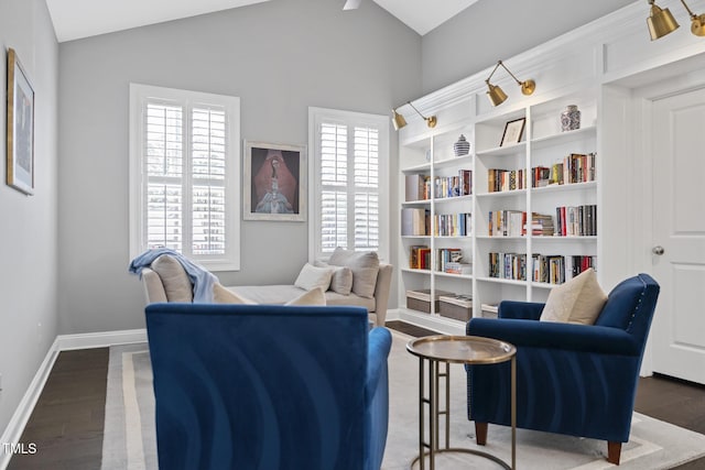 living area featuring baseboards, vaulted ceiling, and wood finished floors