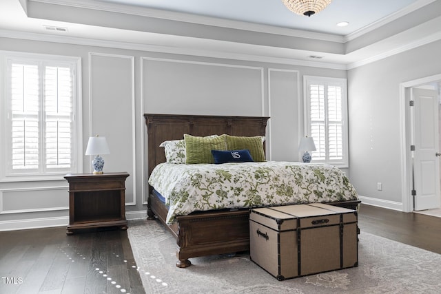 bedroom featuring a raised ceiling, visible vents, a decorative wall, and wood finished floors