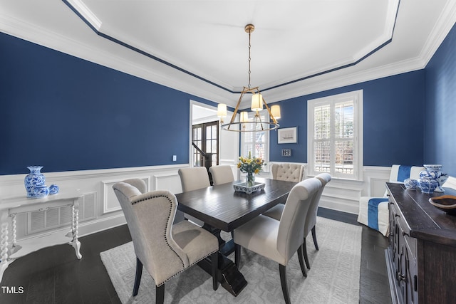 dining area featuring plenty of natural light, visible vents, wood finished floors, and wainscoting