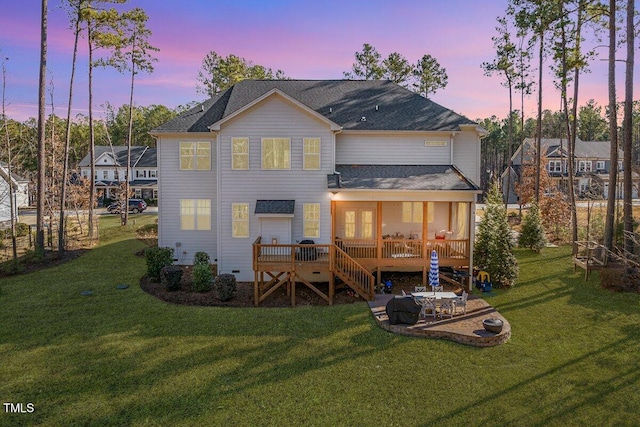 back of property at dusk featuring a deck, a yard, and a patio area