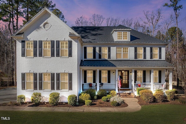 view of front of home featuring covered porch and brick siding