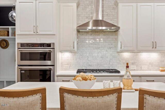 1141 Barley Stone Way, Raleigh, NC 27603 - kitchen with wall chimney range hood, appliances with stainless steel finishes, white cabinetry, light countertops, and tasteful backsplash