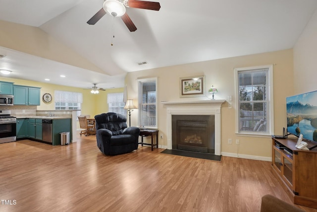 living room featuring ceiling fan, sink, vaulted ceiling, and light hardwood / wood-style flooring