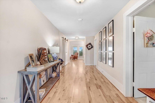 hallway with a barn door and light wood-type flooring