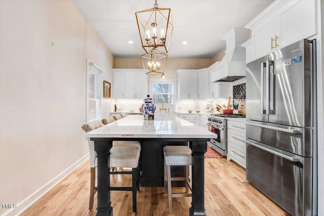 kitchen with white cabinets, premium range hood, stainless steel appliances, and a center island