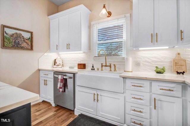 kitchen with light stone countertops, white cabinets, dishwasher, decorative backsplash, and sink