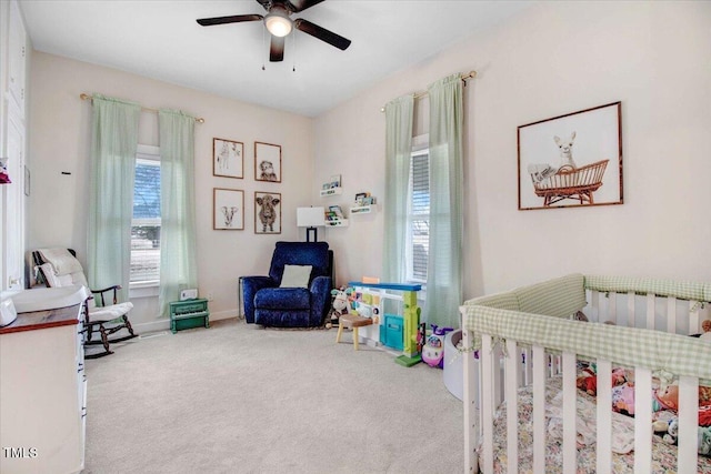 carpeted bedroom with ceiling fan and a nursery area