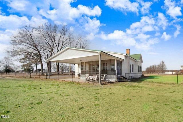 rear view of house with a lawn, a patio, and a sunroom