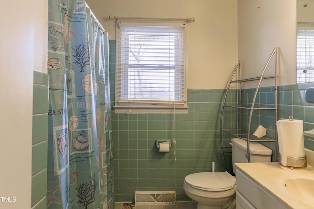 bathroom with toilet, vanity, tile walls, and plenty of natural light