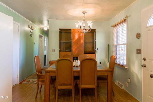 dining area featuring hardwood / wood-style floors, ornamental molding, and a chandelier