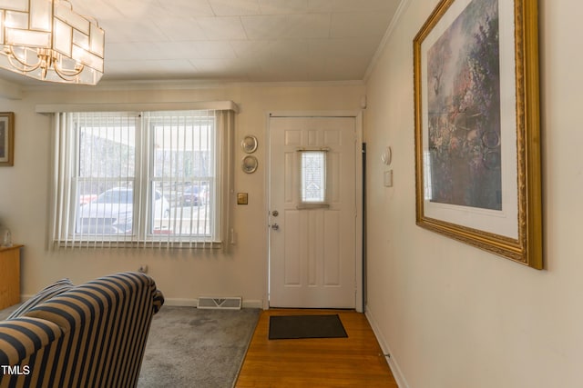 foyer entrance featuring wood-type flooring, crown molding, and a chandelier