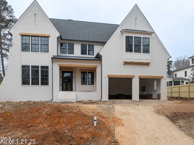 view of front facade featuring an attached garage, driveway, fence, and brick siding