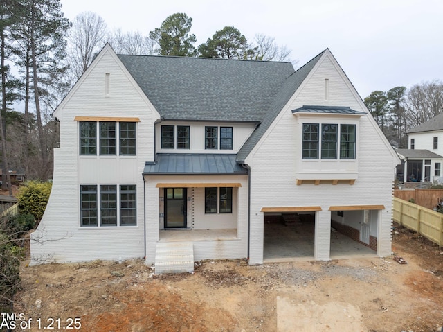 view of front facade featuring metal roof, an attached garage, brick siding, dirt driveway, and a standing seam roof