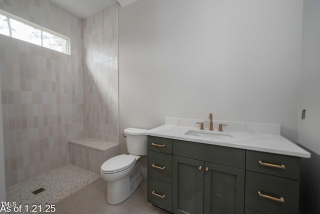 full bath featuring tile patterned flooring, a tile shower, vanity, and toilet